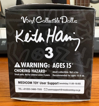 Actual item: side of MEDICOM TOY Keith Haring Series 3 blind box with age warning and support label